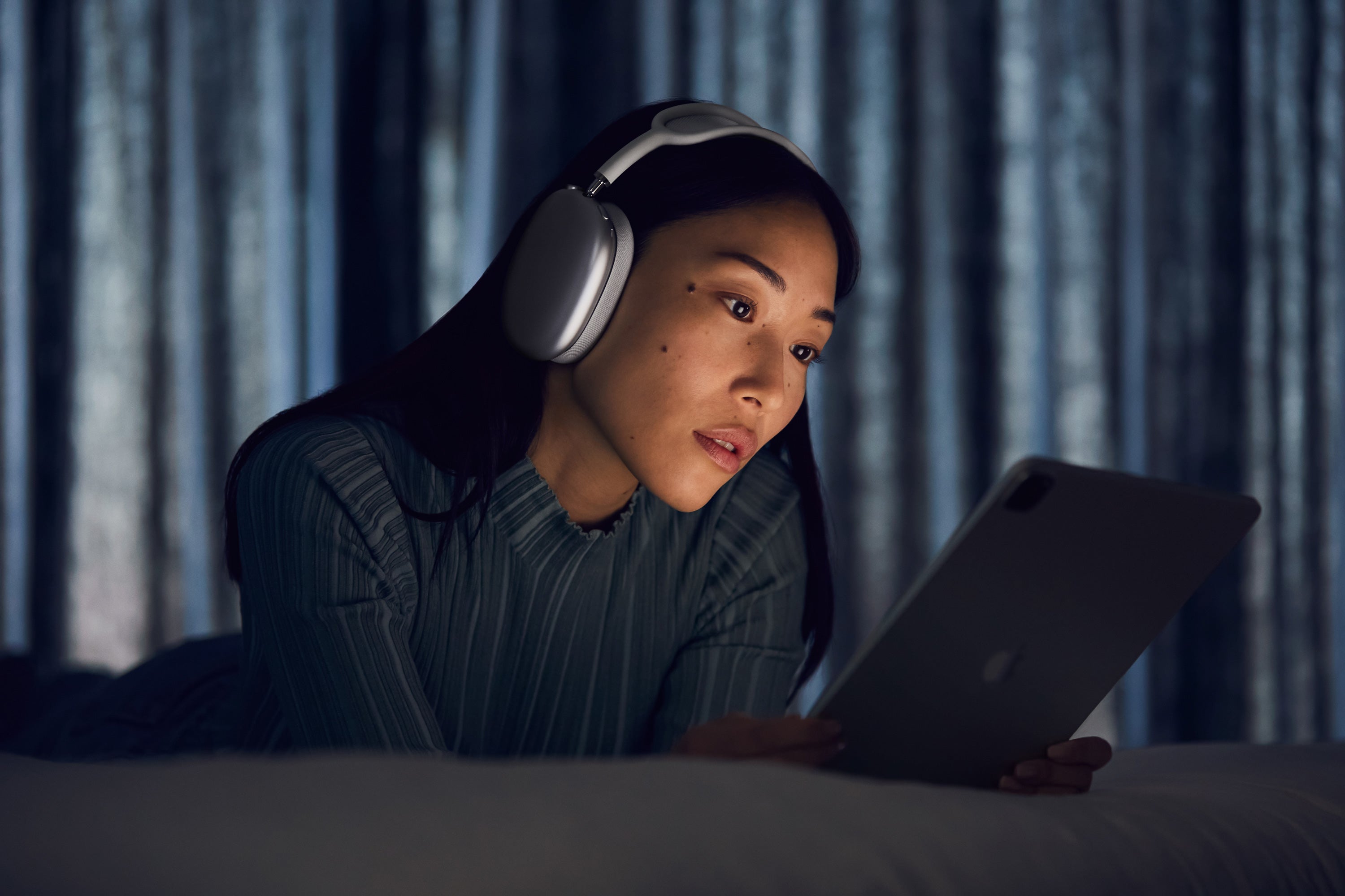 A woman wearing AirPods Max while using a tablet